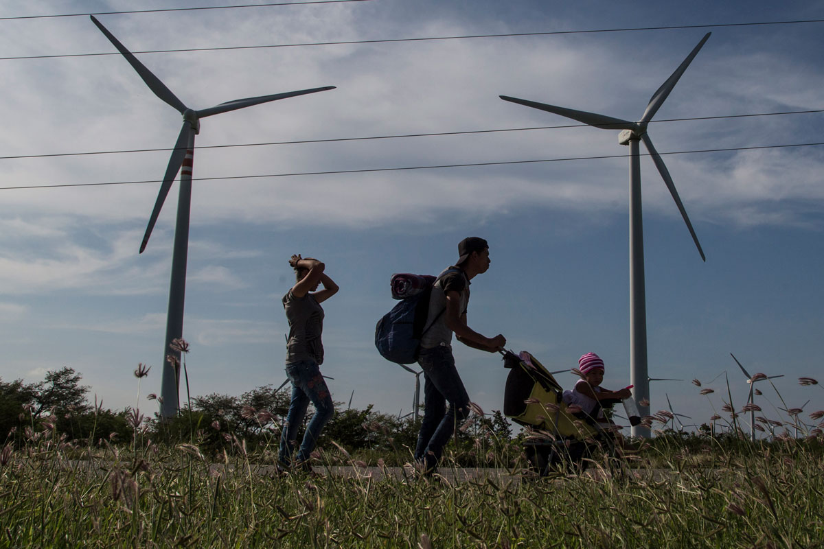 Just Solutions article by Arjun Makhijani featured image of wind mills and a family walking through a field.