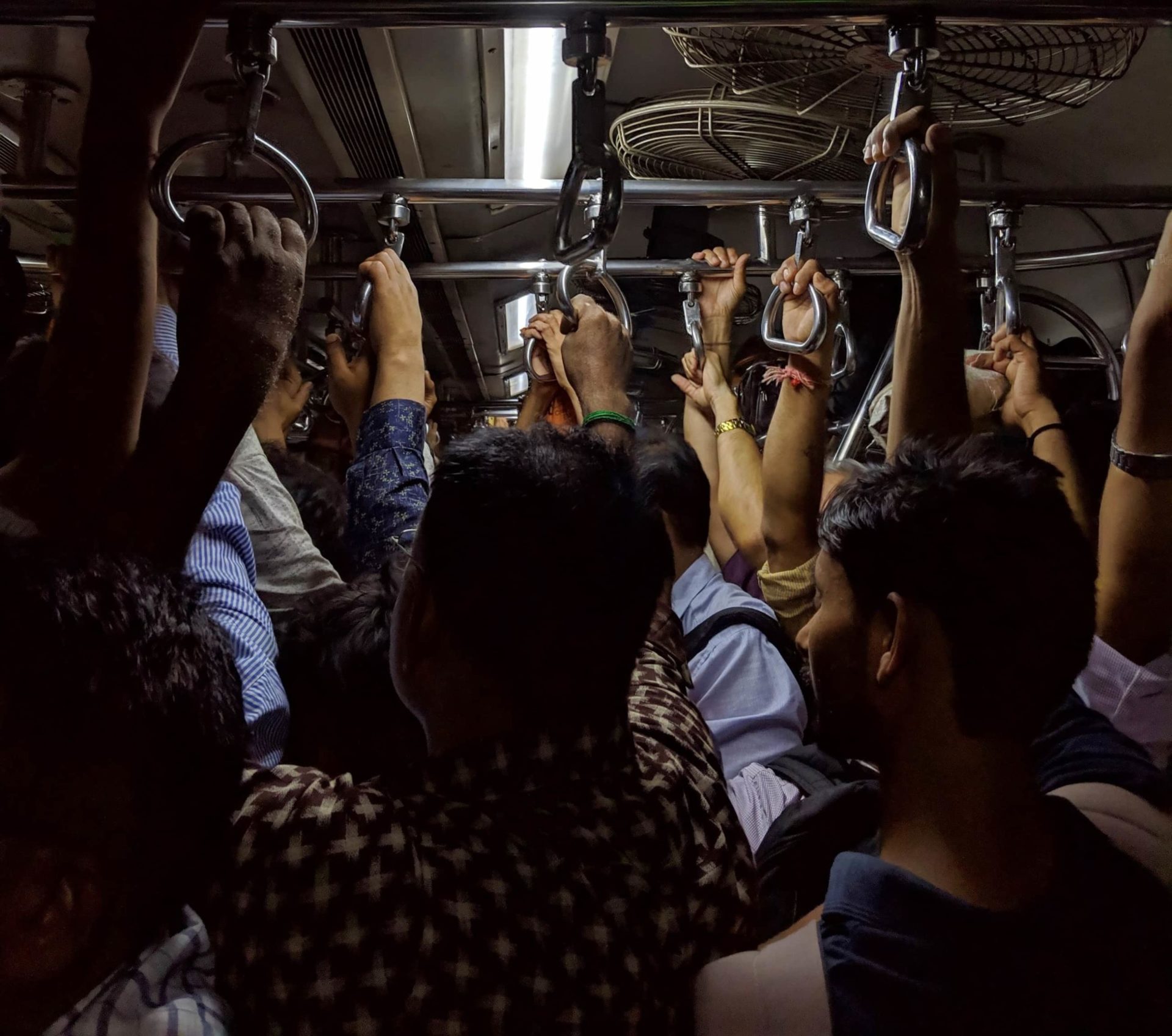 Just Solutions article by Arjun Makhijani featured image of a dark bus with people holding on to the ceiling handles