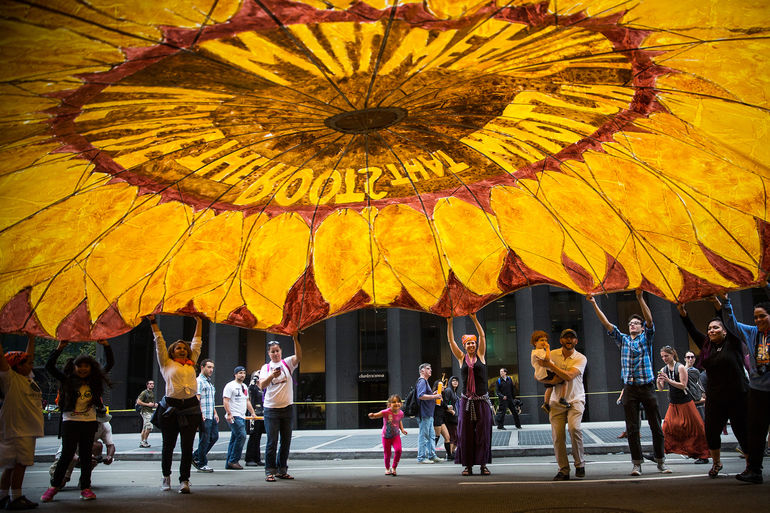 Just Solutions article by Zully Juarez featured image of people lifting a yellow parachute with a sunflower on it