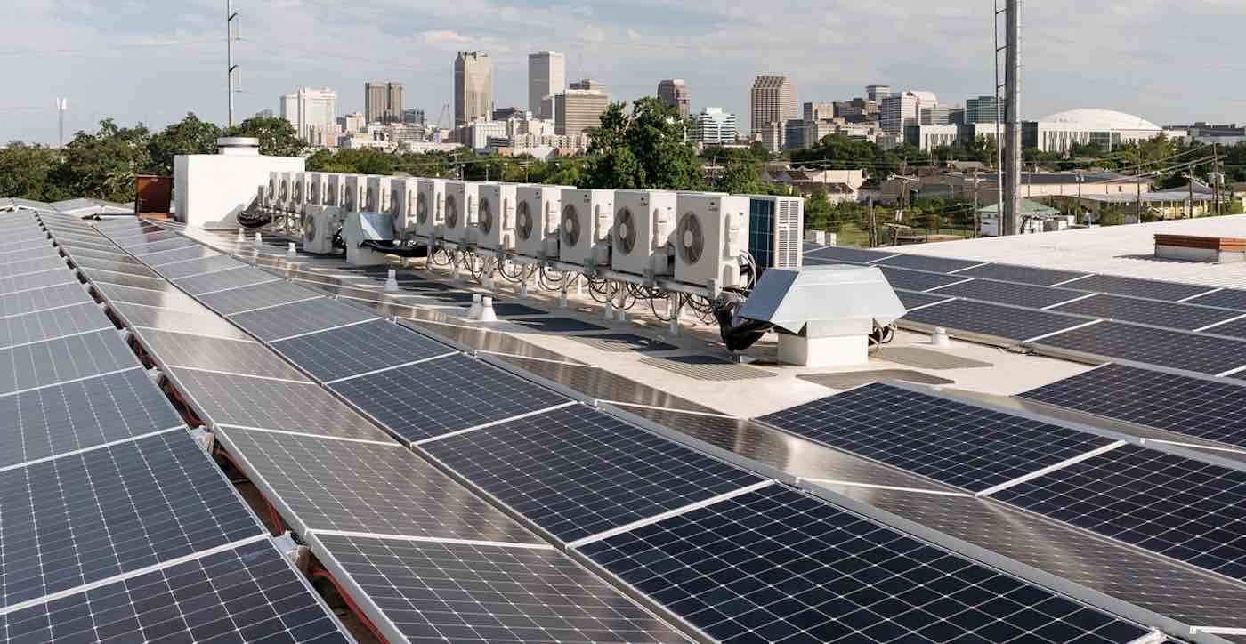 Just Solutions article by Arjun Makhijani featured image of solar panels on a roof with AC units