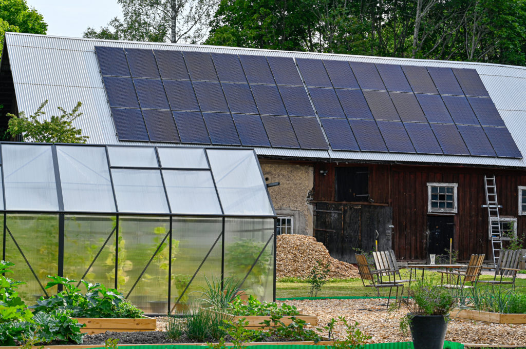 Solar panels on rural farm with greenhouse. The Perfect Storm of Extraction,  Poverty, & Climate Change: A Framework for Assessing Vulnerability,  Resilience, Adaptation, and a Just Transition in Frontline Communities