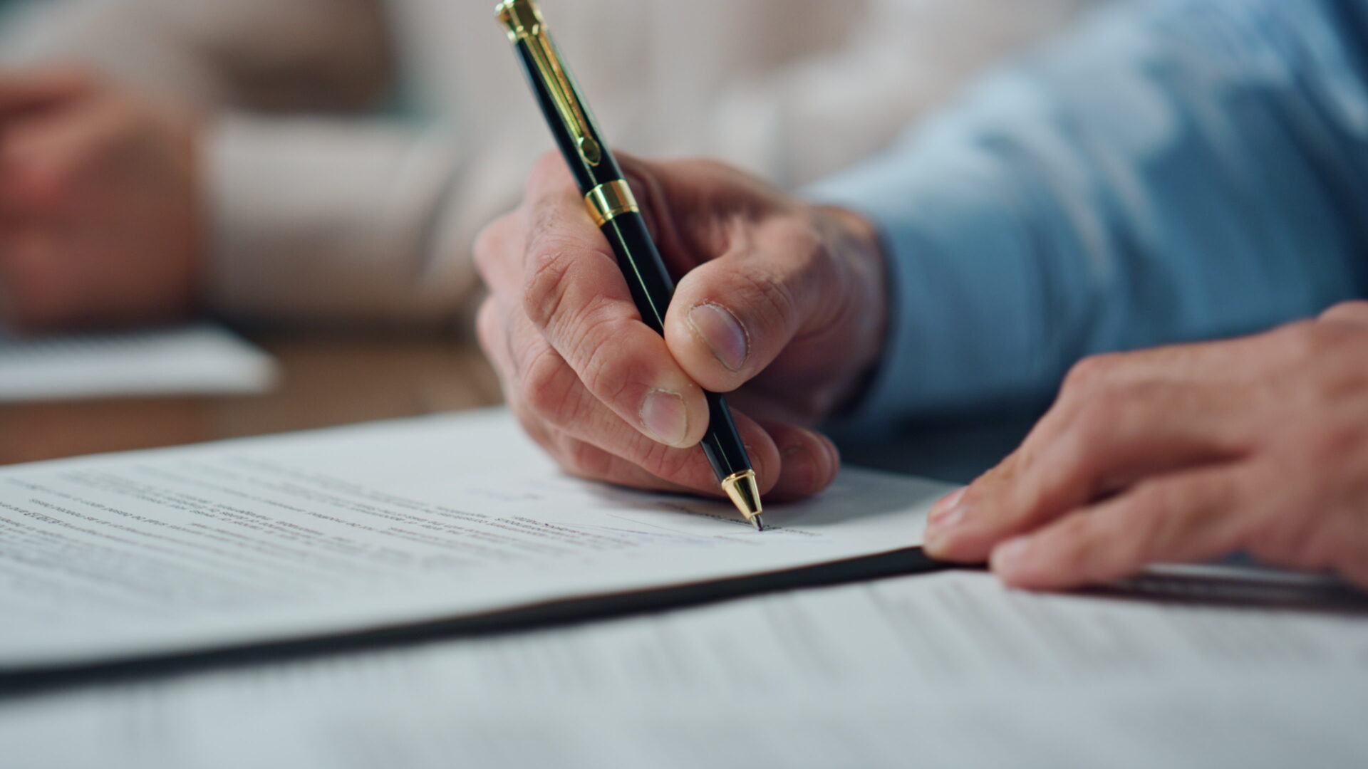 Closeup ceo hands signing contract in office. Unknown successful man holding pen writing on papers. Unrecognized insurance agent checking agreement putting signature. Corporate negotiations concept